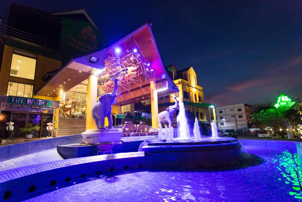 een fontein voor een gebouw 's nachts bij Inn Come Hotel Chiang Rai in Chiang Rai
