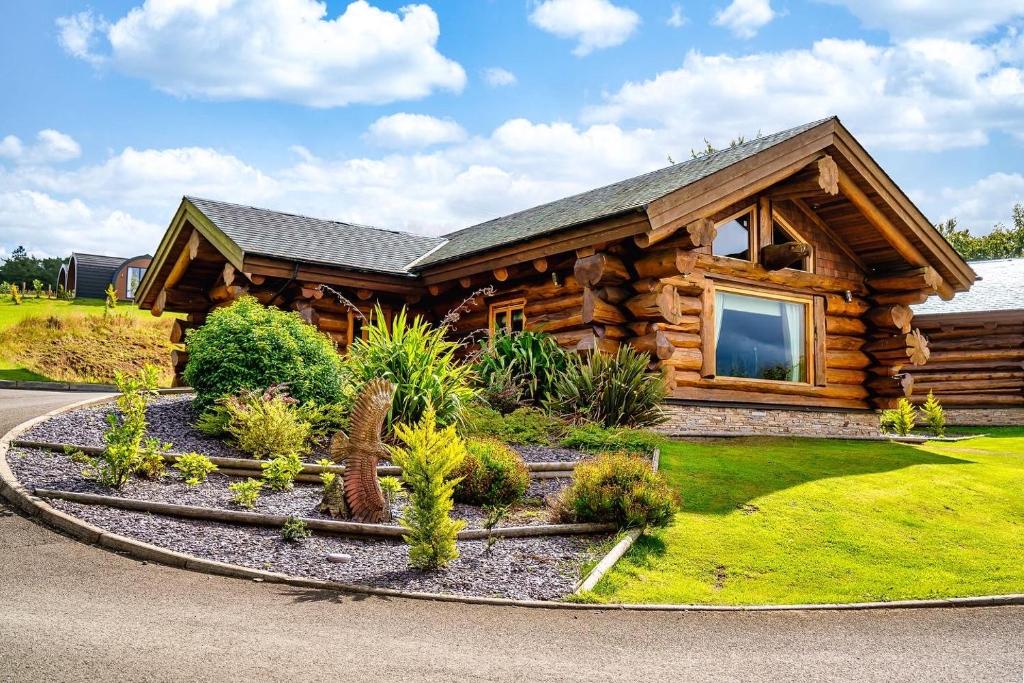 una cabaña de madera con un jardín frente a ella en The Log Cabins at The Vu en Bathgate