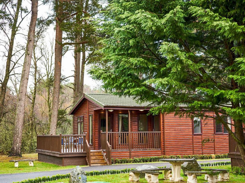 a small cabin in the woods with a deck at Lodge B- Uk33087 in Dinnet