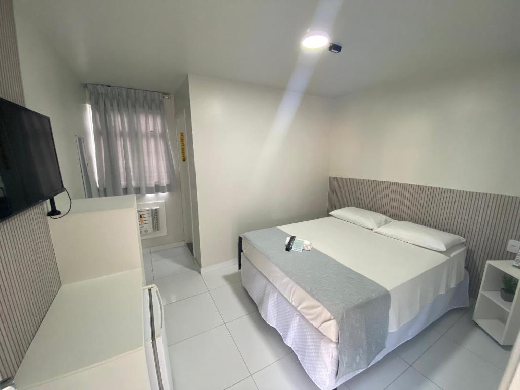 Un dormitorio blanco con una cama y un televisor. en Veleiro Hotel MCZ, en Maceió