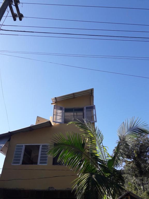 een geel gebouw met een palmboom ervoor bij cantinho bom in Ubatuba