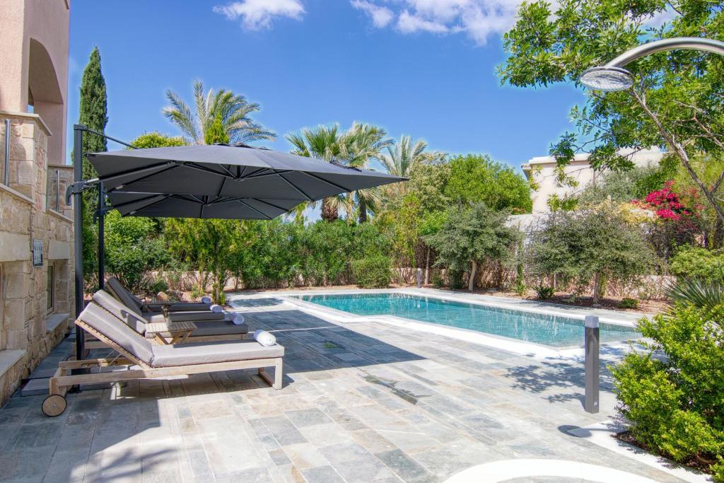 una piscina con 2 tumbonas y una sombrilla en Phaedrus Living Amorosa 13 Beachside Villa en Polis Chrysochous