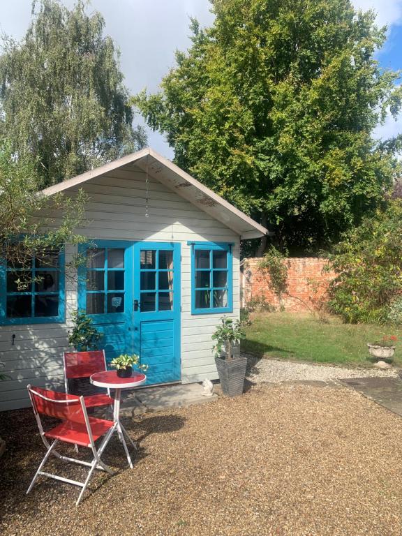 uma casa com uma cadeira vermelha e uma mesa em frente em The Cabin em Spixworth