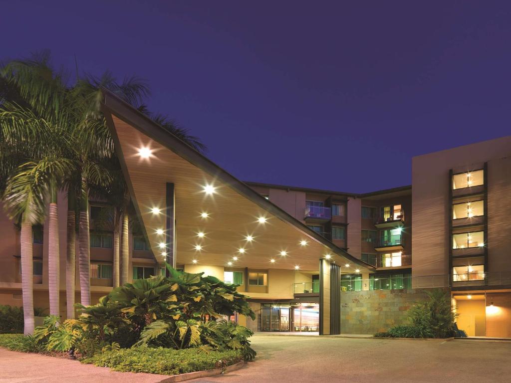 un edificio con palmeras y luces por la noche en Adina Apartment Hotel Darwin Waterfront, en Darwin