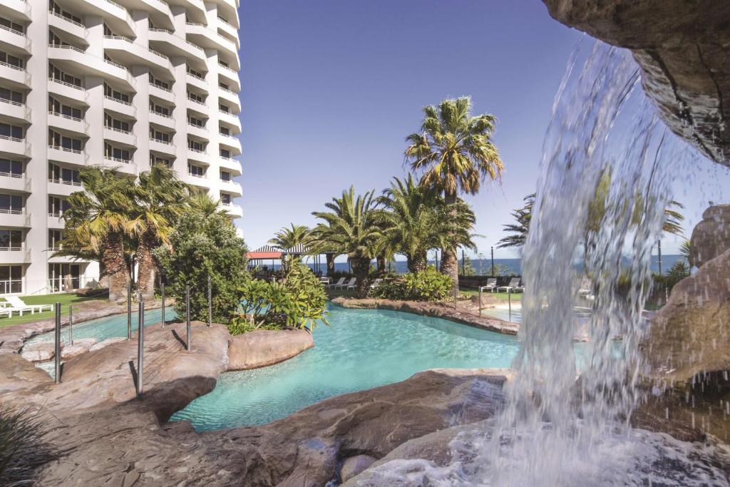 a pool of water with a waterfall in the middle of it at Rendezvous Hotel Perth Scarborough in Perth