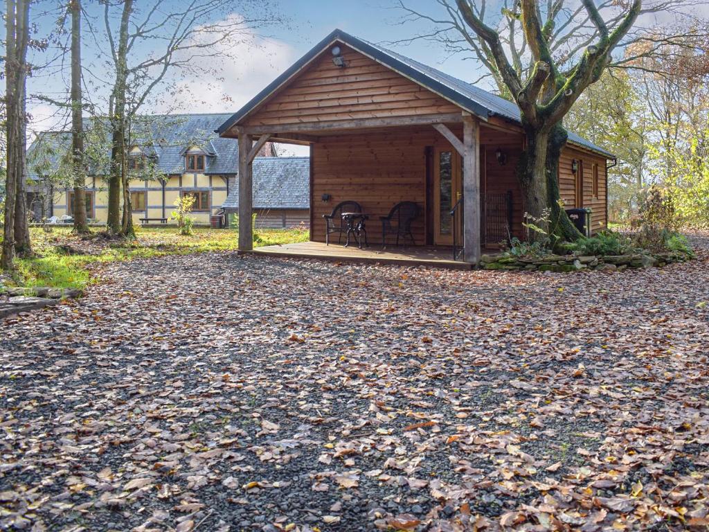 a cabin in the woods with leaves on the ground at Oak Lodge in Edwin Loach