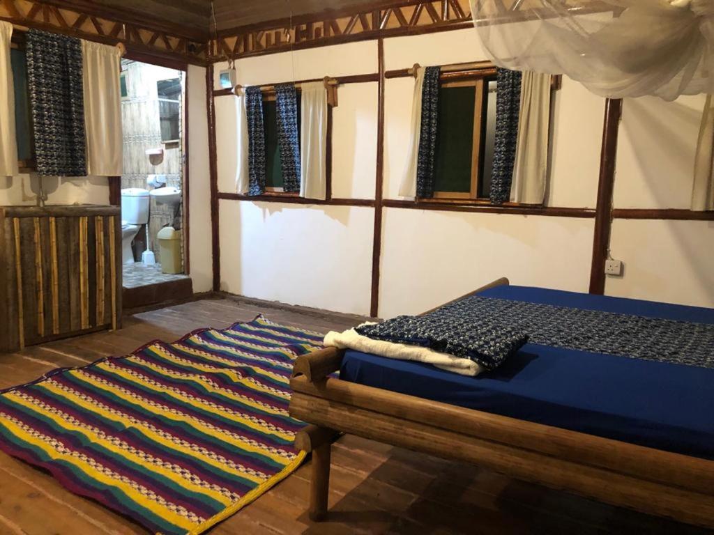 a bedroom with a bed and a rug on the floor at ZIONZURI ARTS ECOVILAGE TREE HOUSE in Mbwamaji