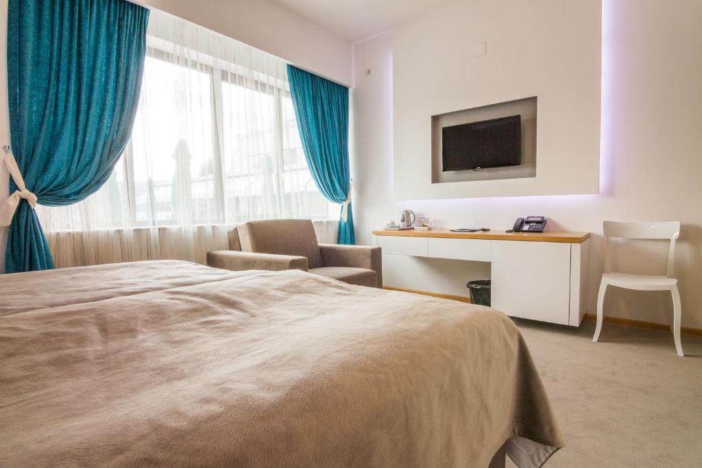 a hotel room with a bed and a desk and a tv at Gardenia Hotel & Spa in Veles