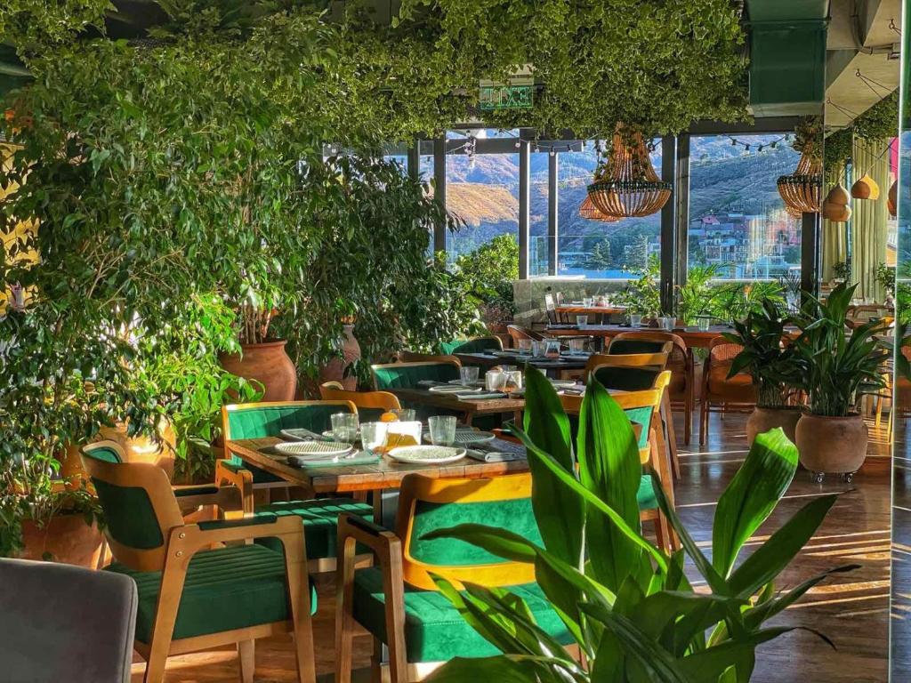 um restaurante com mesas e cadeiras e vasos de plantas em Khedi Hotel by Ginza Project em Tbilisi