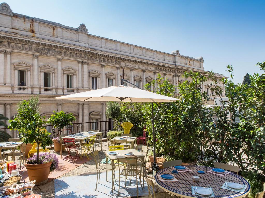 un patio con mesas, sillas y una sombrilla en Salotto Monti en Roma