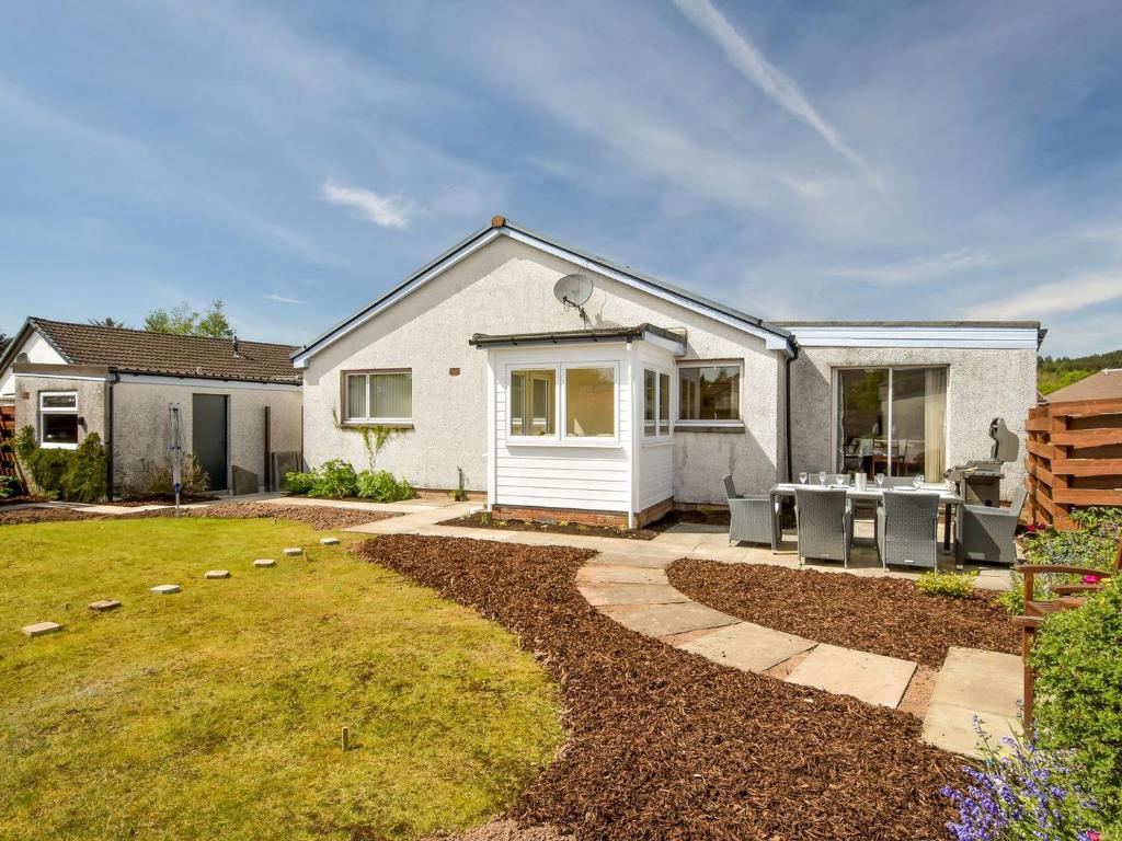 a white house with a patio and a yard at Westburn in Comrie