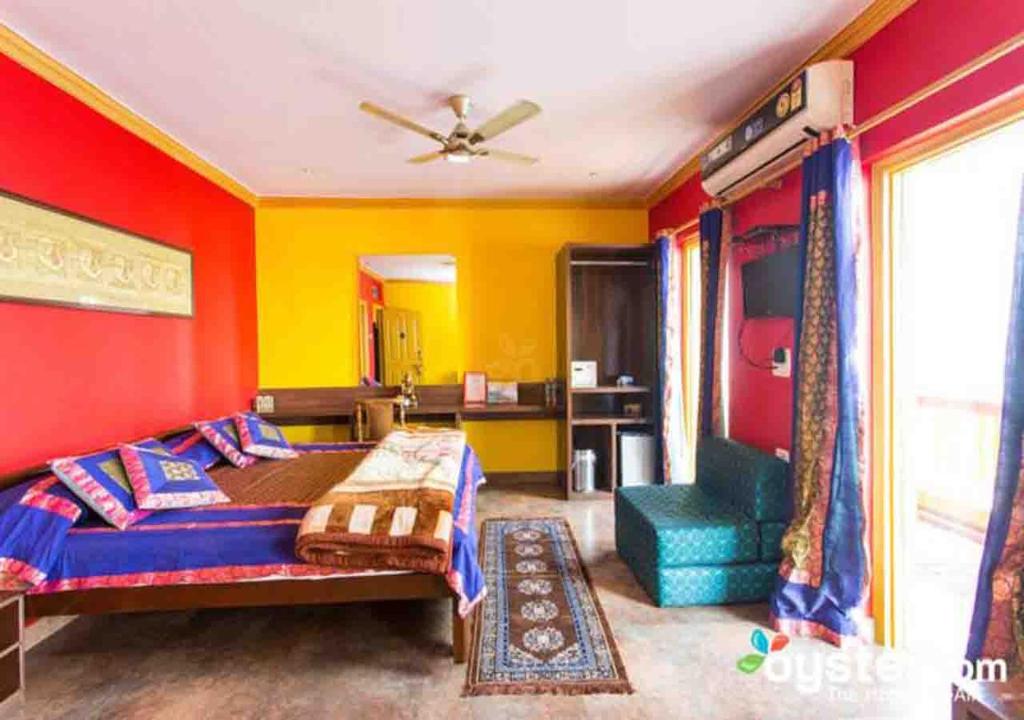 - une chambre avec des murs rouges et jaunes, un lit et une chaise dans l'établissement Ganpati Guest House, à Varanasi