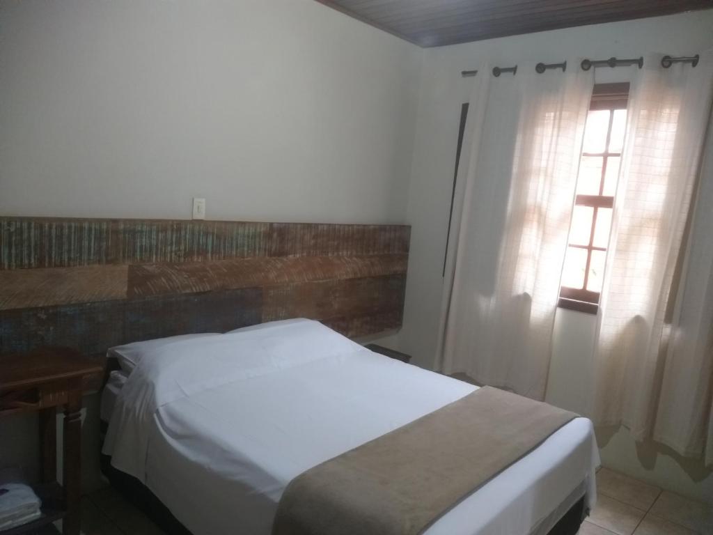 蒂拉登蒂斯的住宿－Suítes Doce Jasmim，卧室配有白色的床和2扇窗户。