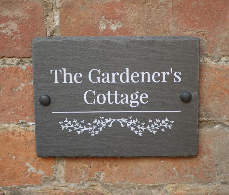 a sign that reads the gardeners cottage on a brick wall at The Gardener's Cottage in Leominster
