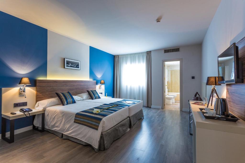 a bedroom with a bed and a desk with a television at Hotel Urban Dream Granada in Granada