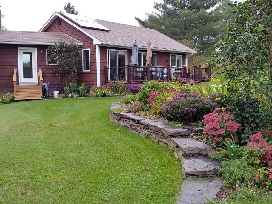 una casa con un patio con un jardín de flores en Spacious country retreat close to town and nature, Sylvana Farm VT, en Montpelier