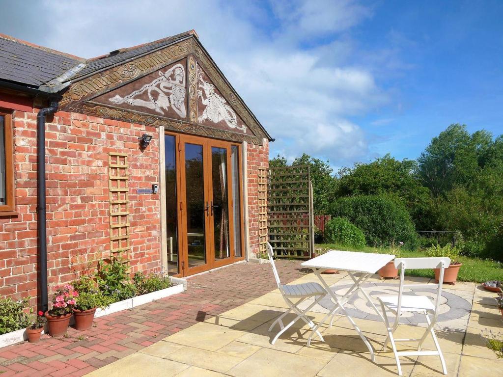 a brick house with a table and chairs on a patio at Spindlestone in Beal