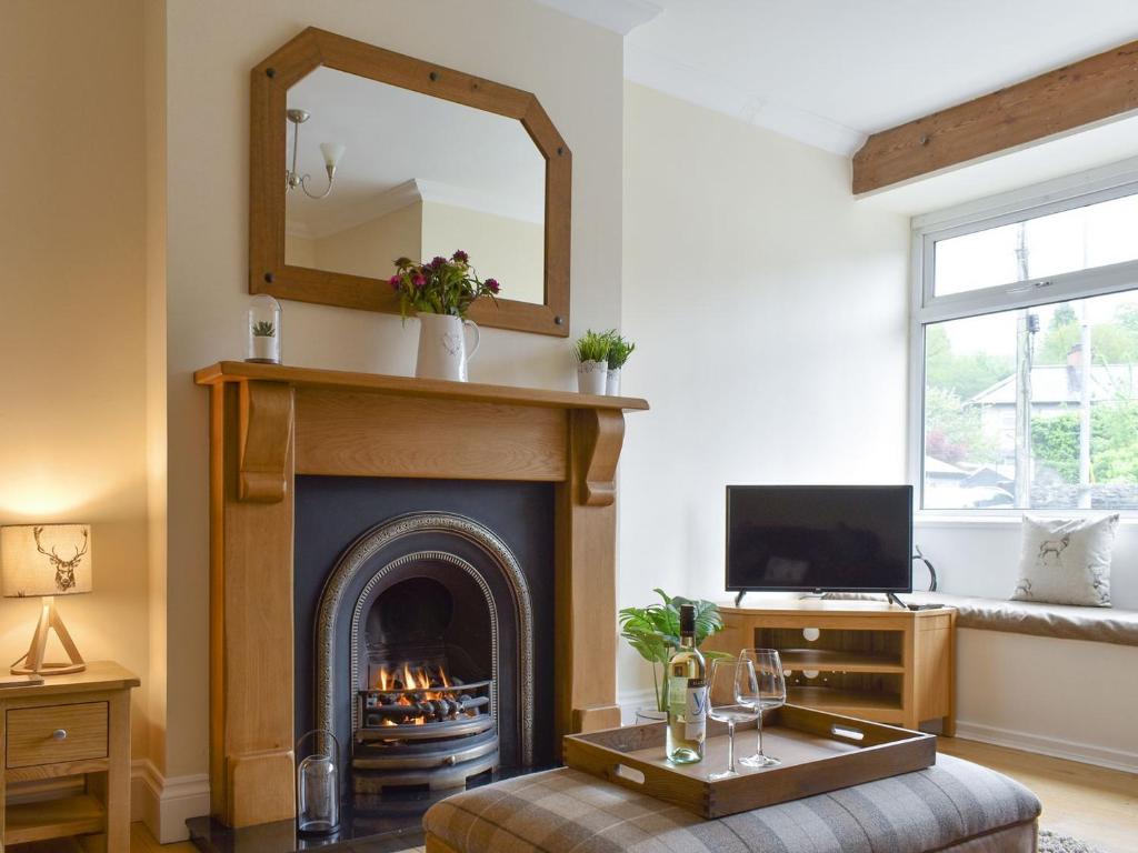 a living room with a fireplace and a mirror at Bwthyn Talaran in Dolgellau