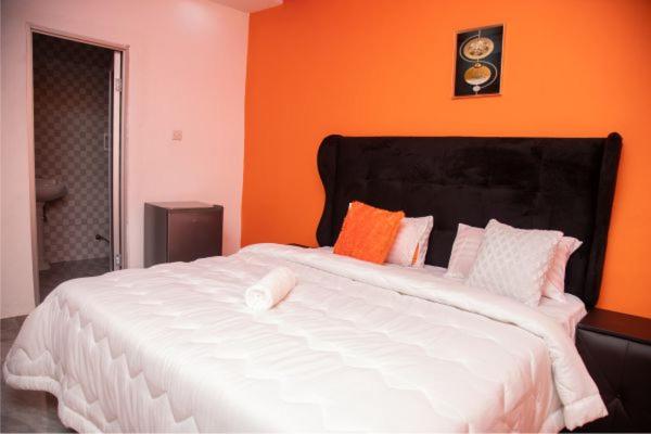 a large white bed in a room with an orange wall at Kasbek Lodge & Tours in Kazungula