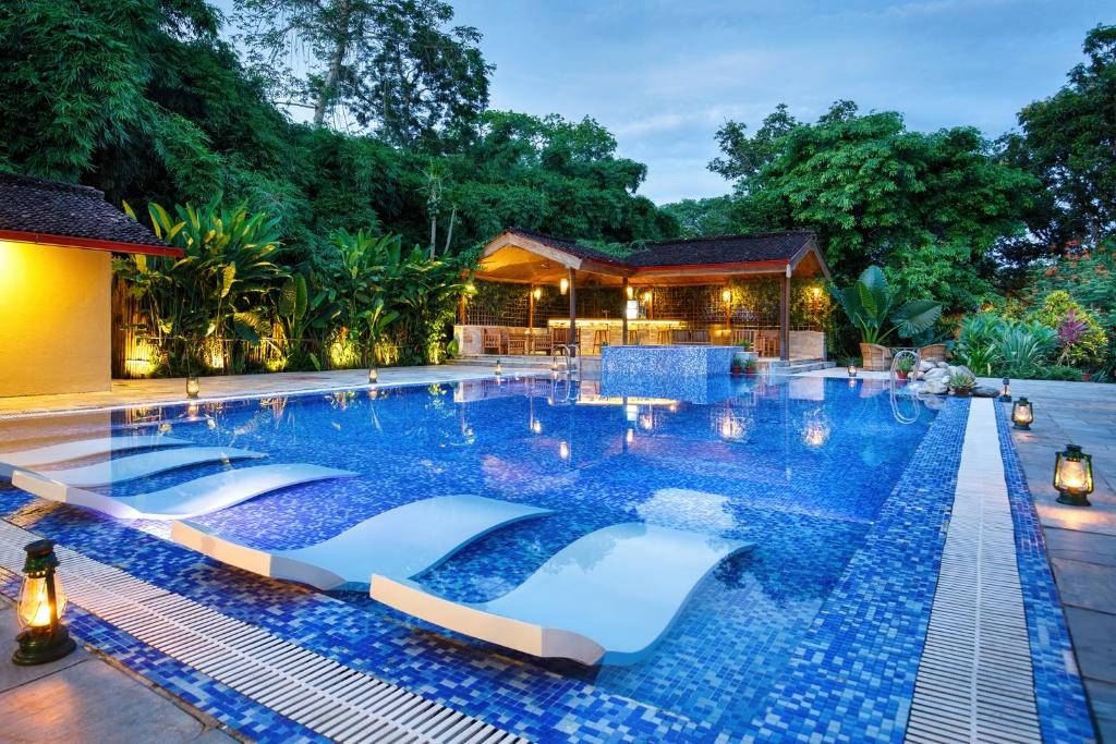 een zwembad in een resort met blauwe tegels bij Green Mansions Jungle Resort in Sauraha
