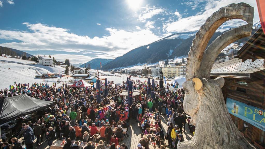 a large crowd of people standing around a ski slope at Hotel Steinbock in Klosters