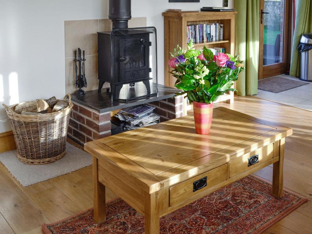 a living room with a wooden coffee table with flowers on it at Little Hendre Lodge - Uk10262 in Penrhôs