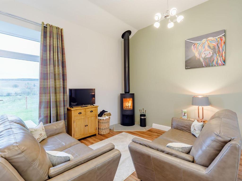 a living room with two couches and a tv at Merry Burn Barn - Uk3325 in Falstone