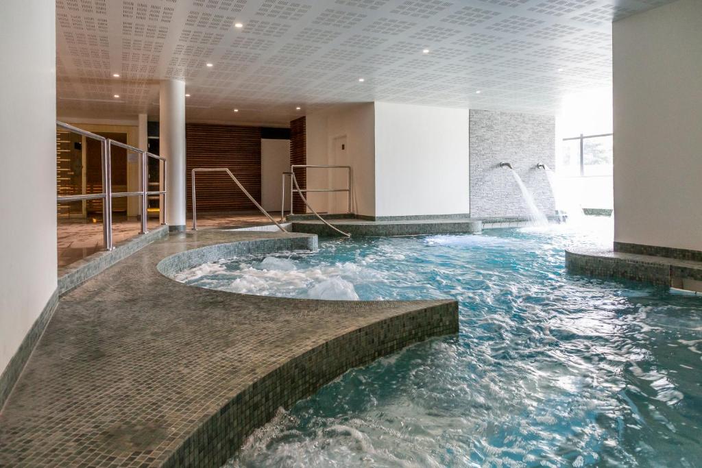 - une grande piscine intérieure d'eau dans un bâtiment dans l'établissement Nemea Appart Hotel Les Hauts de Milady Biarritz, à Biarritz