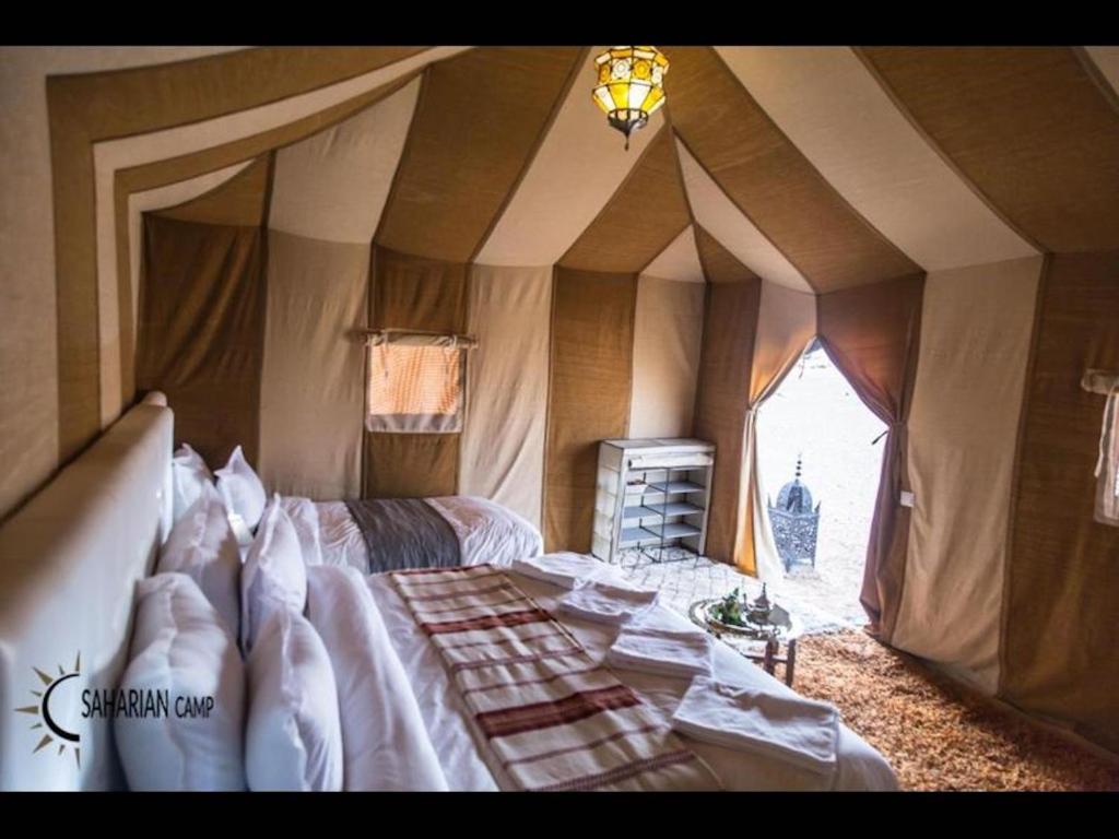 a bedroom with a bed in a tent at Deluxe triple room for three at Saharian Luxury Camp in Tisserdmine