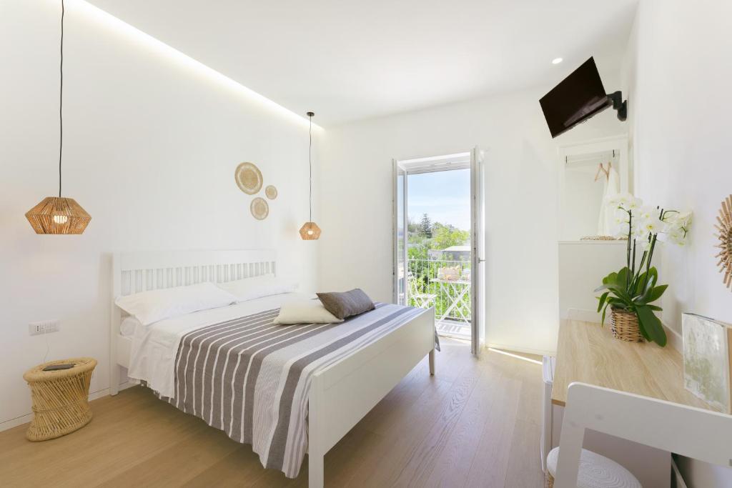 Sea More في بروسيدا: غرفة نوم بيضاء مع سرير وشرفة