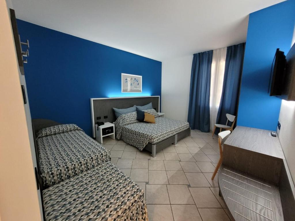 a bedroom with two beds and a blue wall at Maritan Hotel & Spa in Padova
