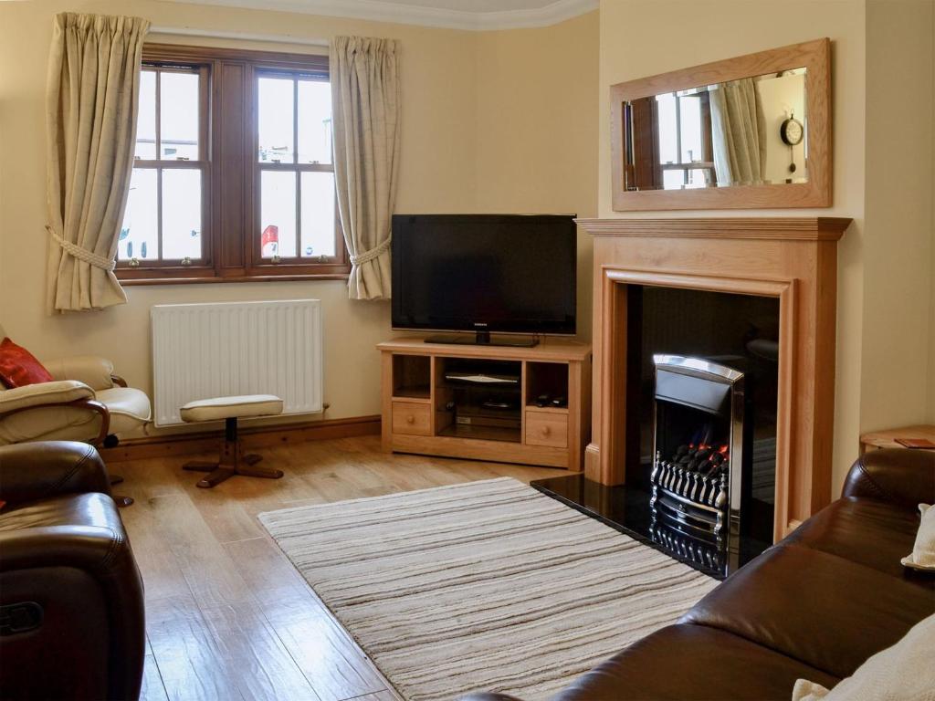 a living room with a television and a fireplace at Bridge Street Close in Cockermouth