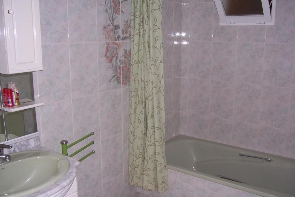 a bathroom with a tub and a sink and a shower curtain at Pensión Nomphosumus in Cala del Moral