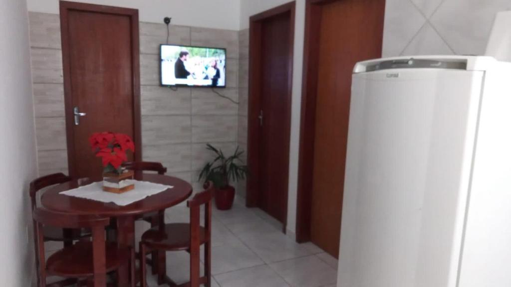 uma sala de jantar com uma mesa e cadeiras e uma televisão em Apartamento a poucos minutos do Aeroporto de Floripa e das Praias do Sul da Ilha em Florianópolis