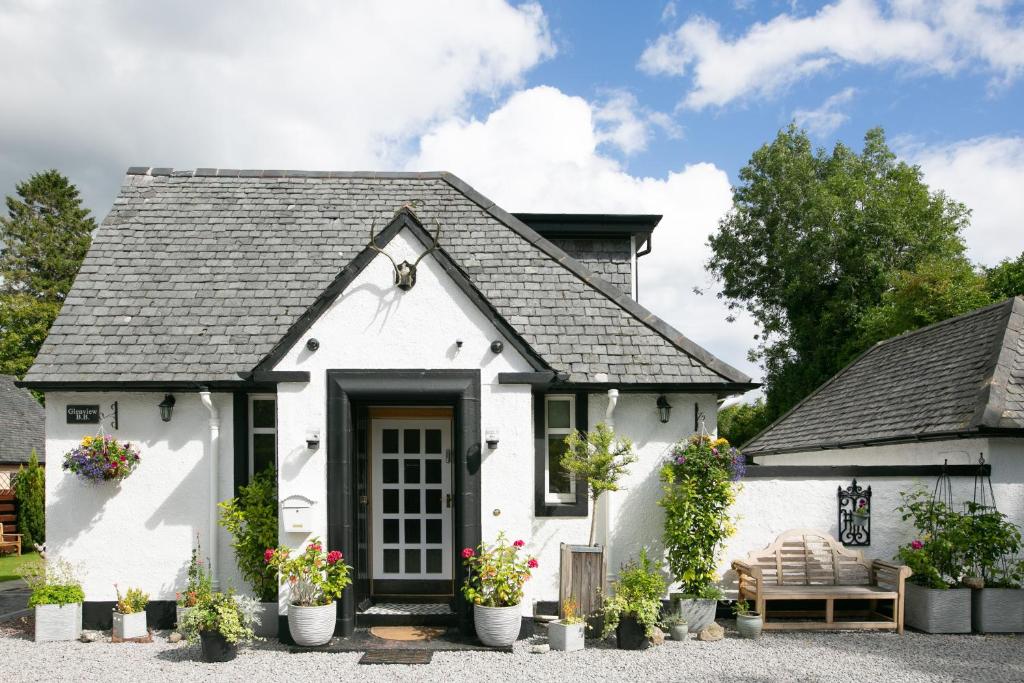 a white cottage with a black door at Glenview Luss in Luss