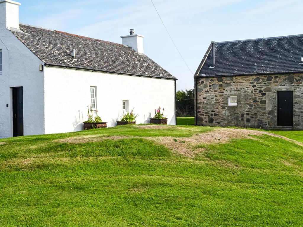 an old stone house with a green lawn in front of it at Ferrycroft 1 - Uk33395 in Isle of Gigha