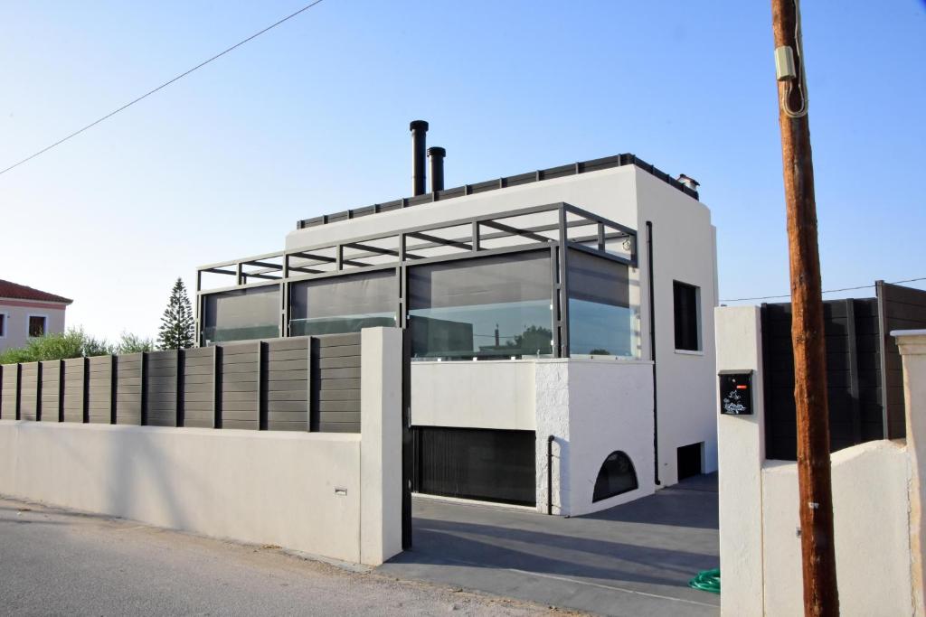 a white building with glass windows on a street at White and Black Aegina in Áyioi Asómatoi