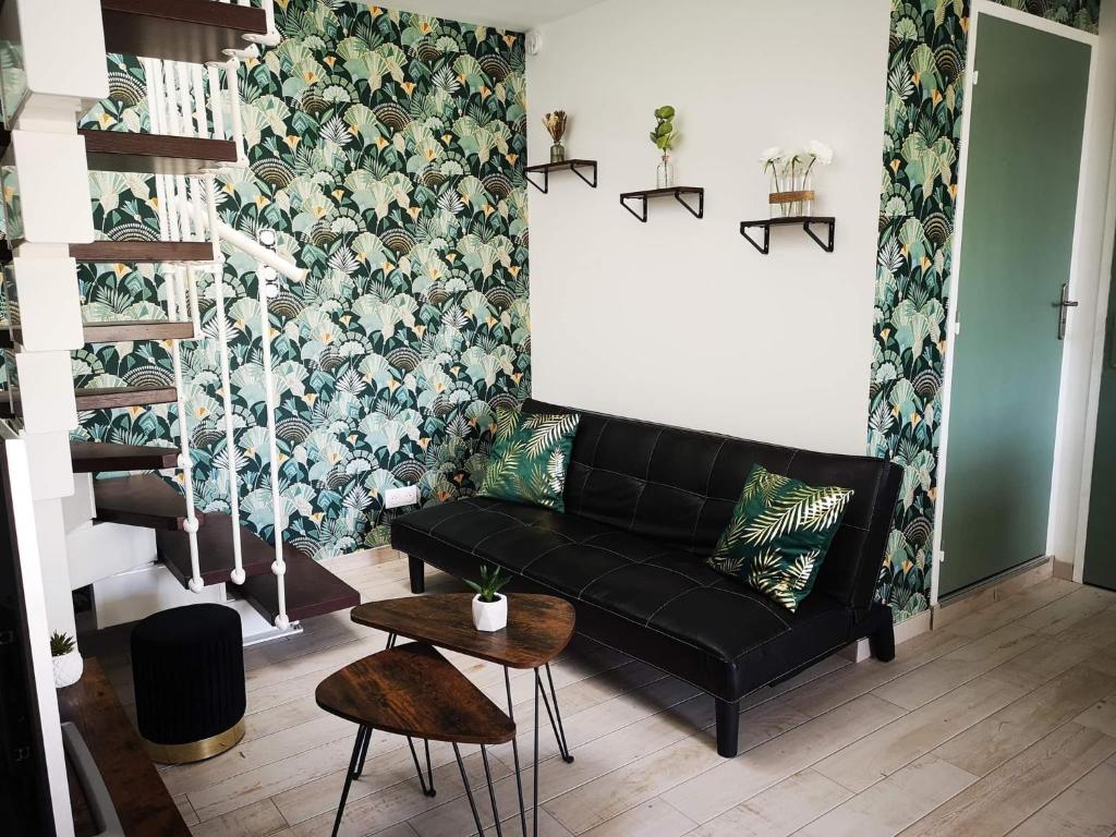 a living room with a black couch and floral wallpaper at Le Séduisant in Sainte-Anne-sur-Vilaine