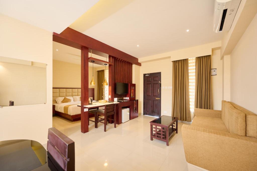 a hotel room with a bed and a living room at Thekkady Gavi Suites in Vandiperiyār