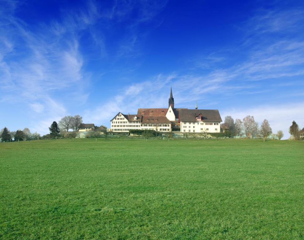 un gran edificio en un campo con un campo verde en Kloster Kappel, en Kappel am Albis