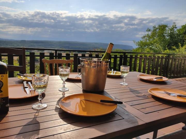 una mesa de madera con una botella de vino y copas en Chez Sam en Villebois