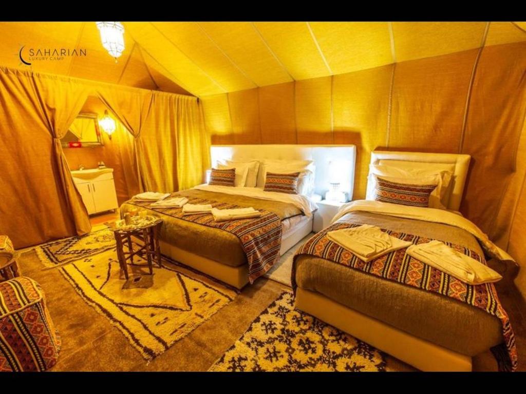 a bedroom with two beds in a tent at Over night at Merzouga Sahara Desert in Tisserdmine