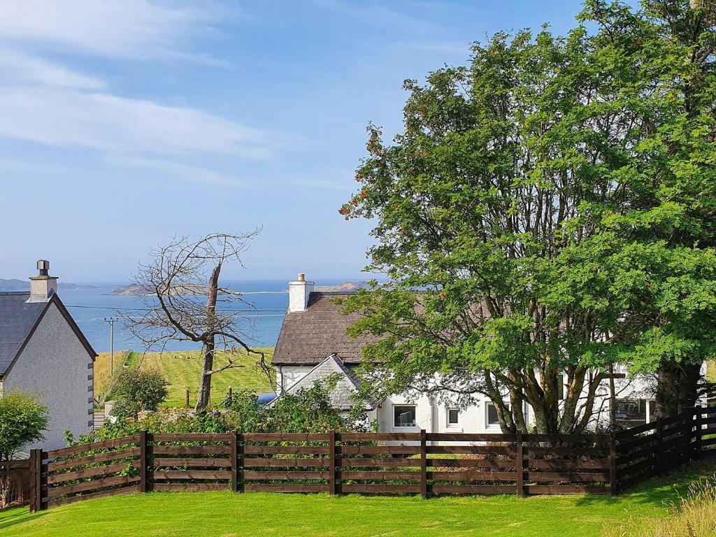 a wooden fence in front of a house with a tree at Tor Aluinn in Skullomie