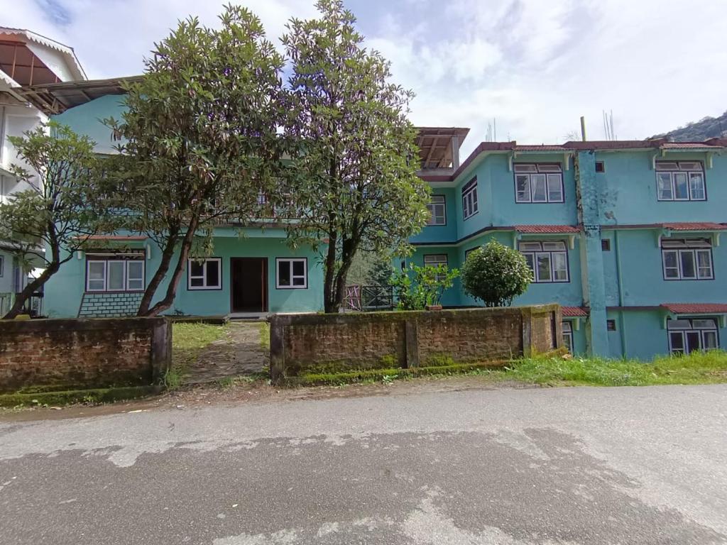 una casa azul al lado de una calle en Hotel Pemathang en Pemayangtse