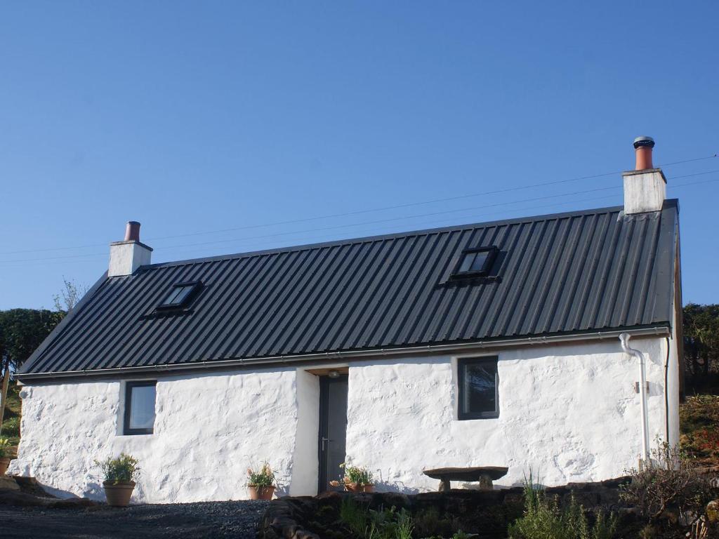 une maison en pierre blanche avec un toit noir dans l'établissement An Airigh, à Dunan