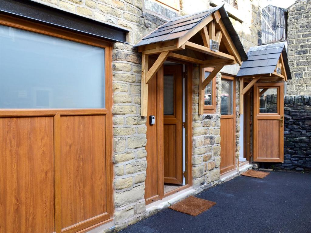 a row of wooden garage doors on a stone building at Chunal Apartment - Uk12958 in Glossop