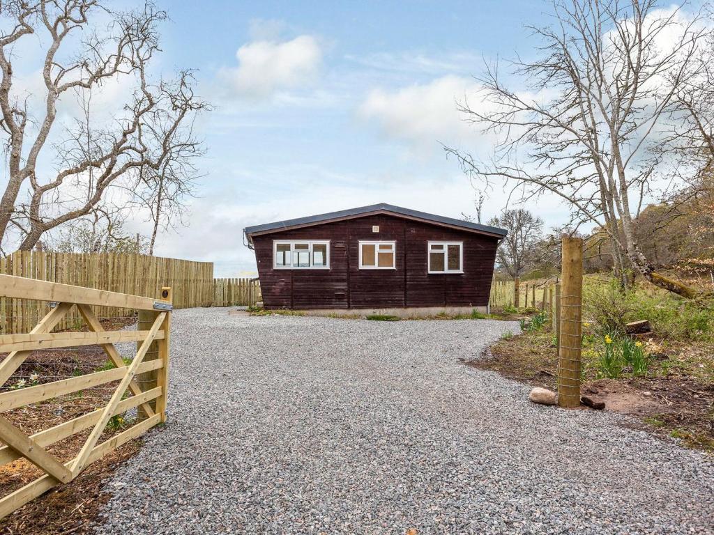 a small wooden house with a fence and a gravel driveway at Kilninver - Uk31537 in Kirkhill