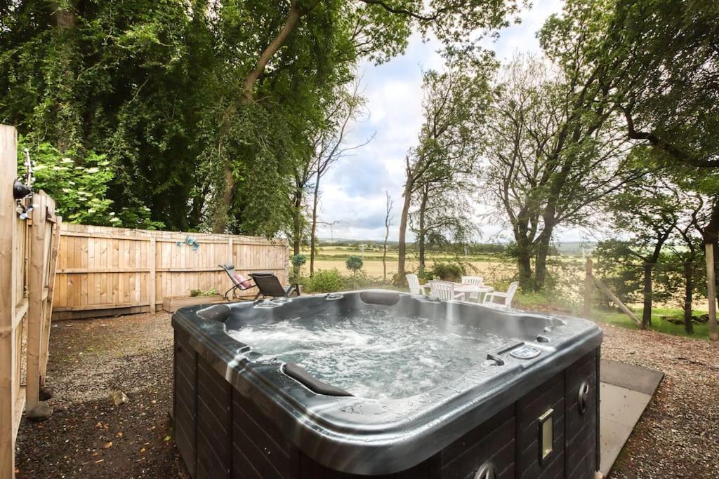 a hot tub in a yard next to a fence at Hayloft at Bonnyside House in Bonnybridge