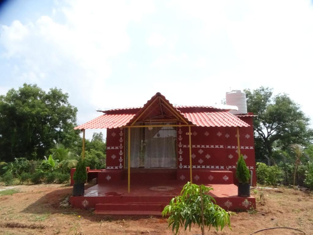 a small red house with a red roof at MangoHut Farmhouse Pool Villa in Hyderabad