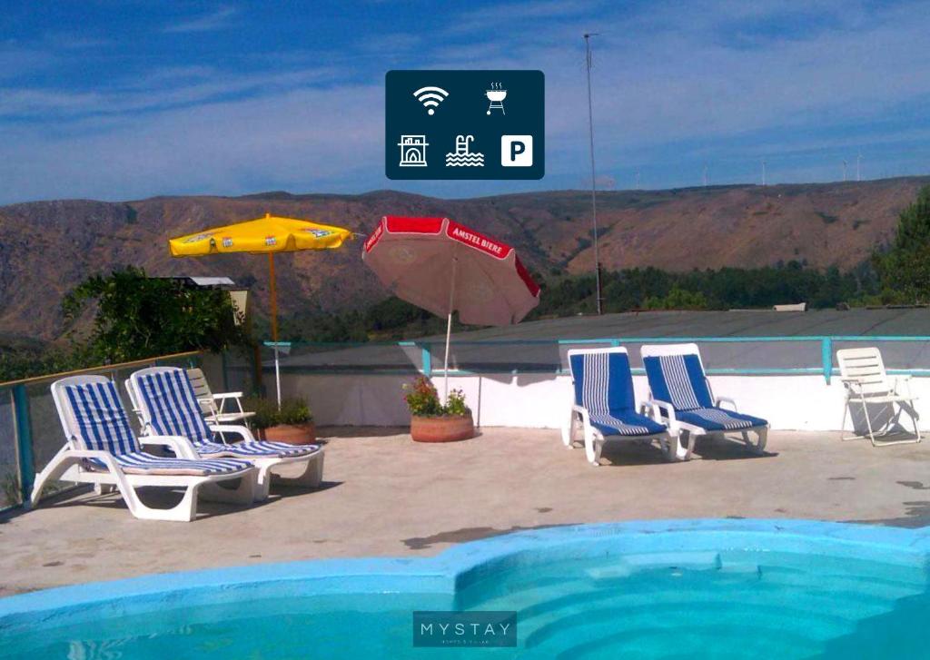 a group of chairs and an umbrella next to a pool at MyStay - Quinta do Tendeiro in Guarda